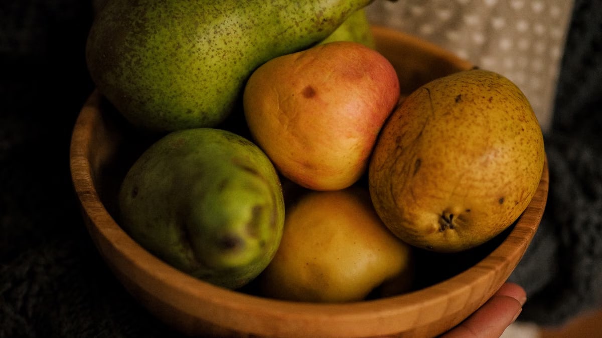 A wooden bowl holding an assortment of pears and apples, highlighting healthy eating.